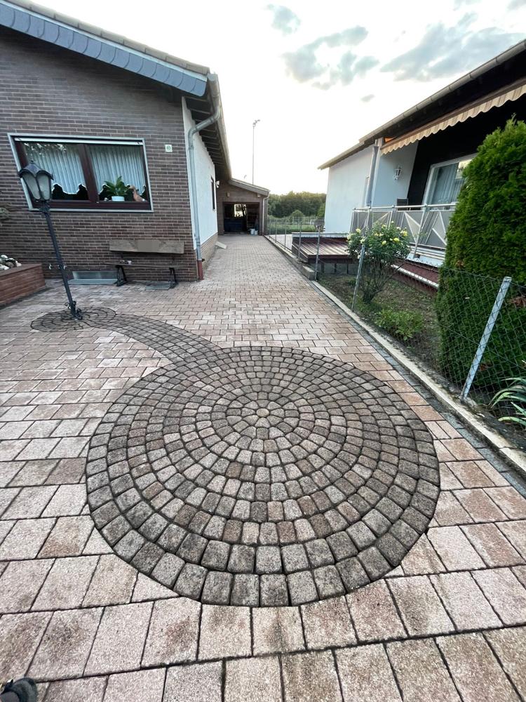 Fertig gereinigter Hof mit Pflasterkreis aus Kopfsteinen vor einem Haus