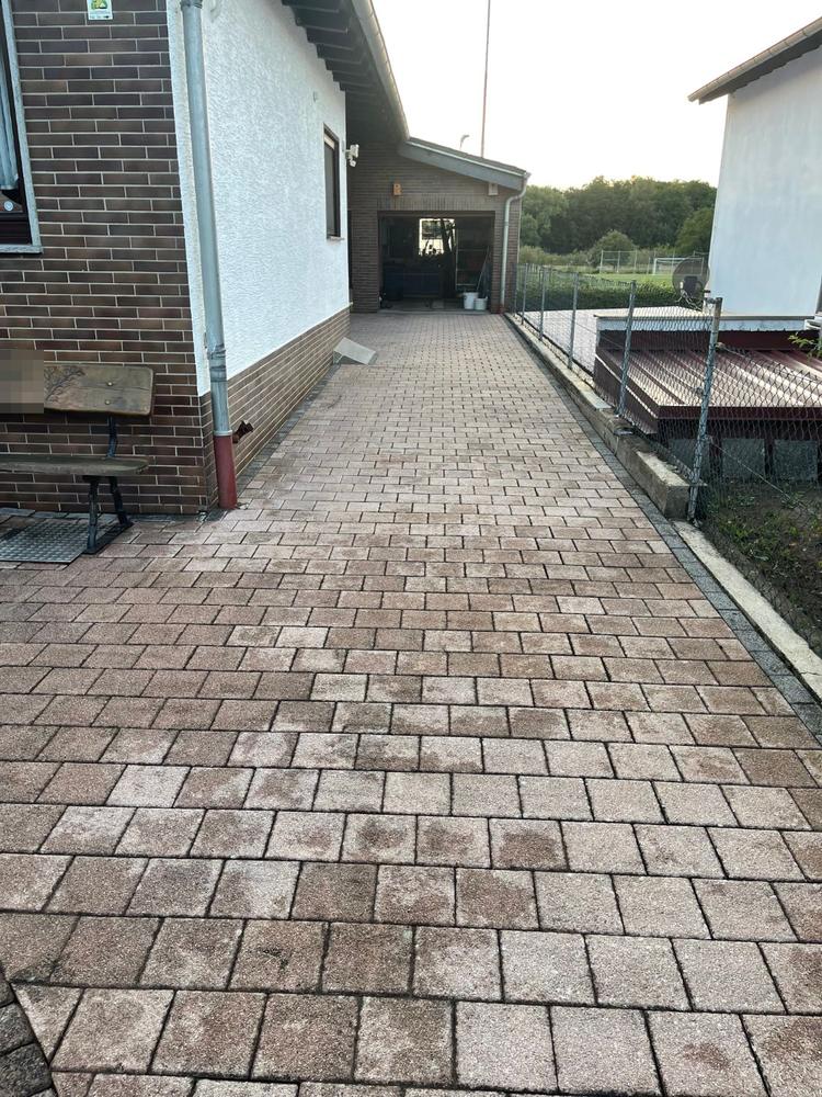 Gereinigter Pflasterweg entlang des Hauses bis zur Garage